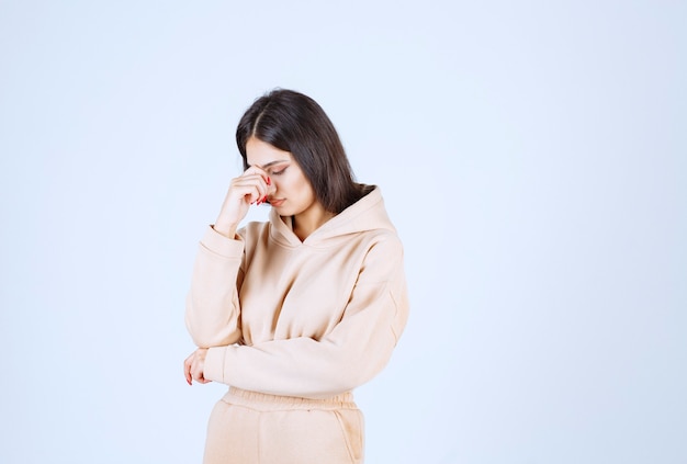 Foto gratuita mujer joven en una sudadera con capucha rosa sosteniendo la cabeza mientras tiene dolor de cabeza