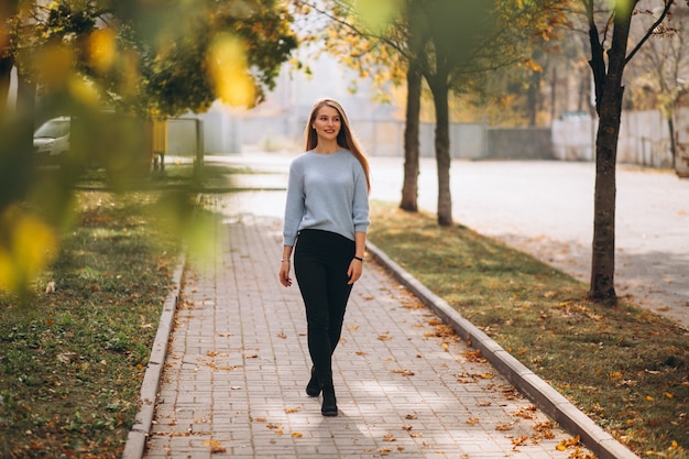 Mujer joven en suéter azul en el parque otoño