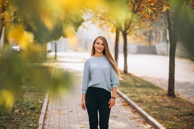 Mujer joven en suéter azul en el parque otoño