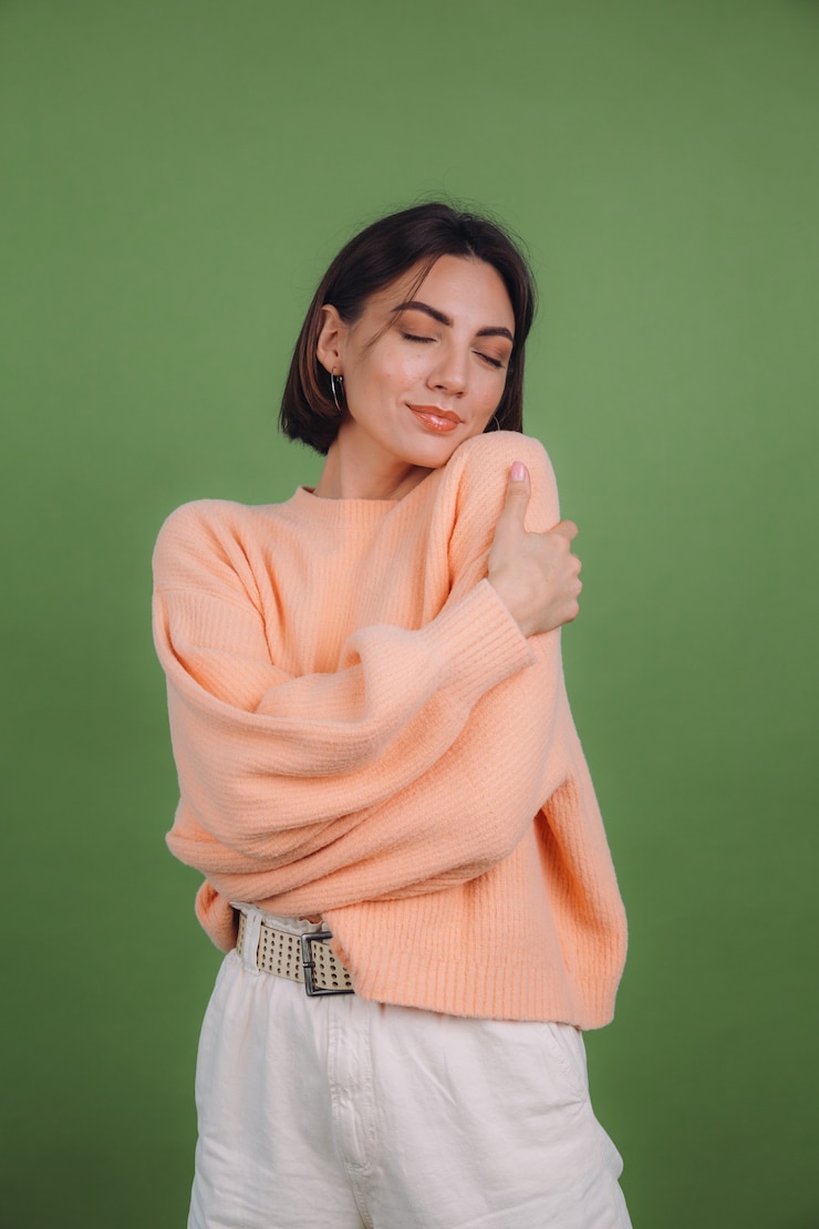 Foto gratuito mujer joven en suéter de melocotón casual aislado en la pared de color verde oliva