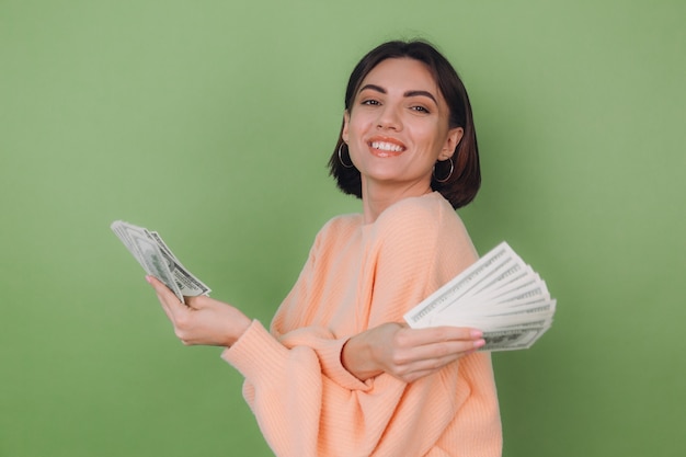 Foto gratuita mujer joven en suéter de melocotón casual aislado en la pared verde oliva