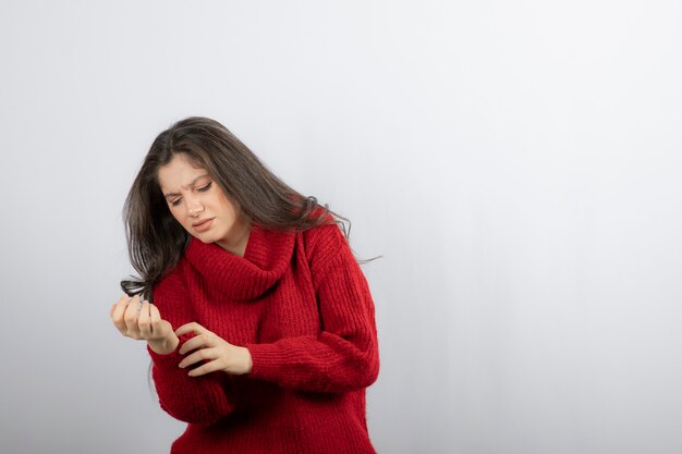 Mujer joven en suéter rojo cálido que sufre de dolor en el brazo.