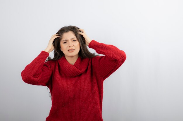 Mujer joven en suéter rojo caliente que sufre de dolor de cabeza.