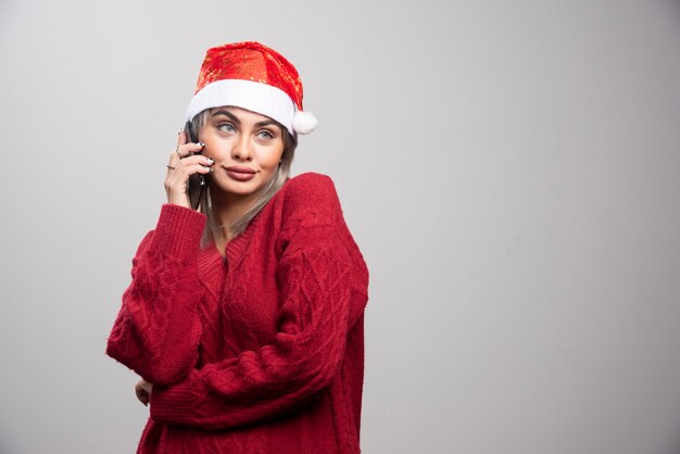 Mujer joven en suéter rojo hablando por teléfono celular.