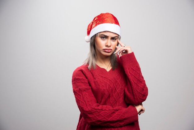 Mujer joven en suéter rojo pensando intensamente.