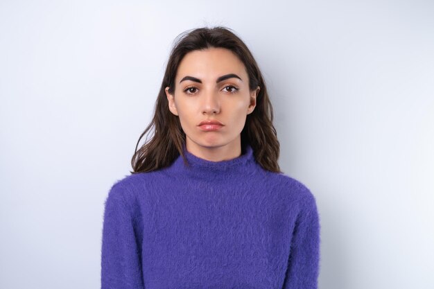 Mujer joven en suéter suave y acogedor púrpura en el fondo molesto