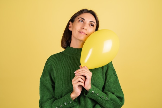 Mujer joven en suéter verde cálido sonriendo con globo de aire