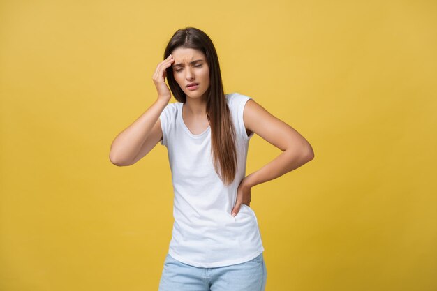 Mujer joven sufre de dolor de cabeza contra un fondo amarillo Foto de estudio
