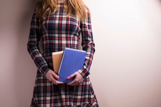 Mujer joven sujetando dos libros junto a su barriga