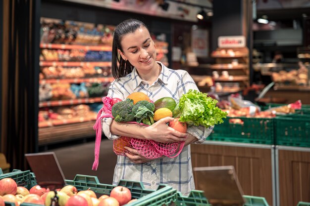 Mujer joven en un supermercado con verduras y frutas comprando comestibles