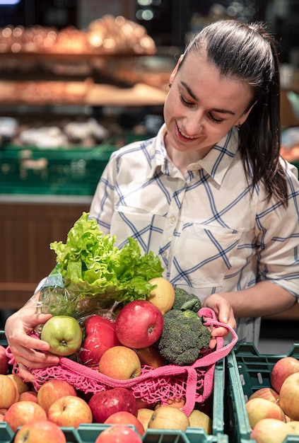 Mujer joven en un supermercado con verduras y frutas comprando comestibles