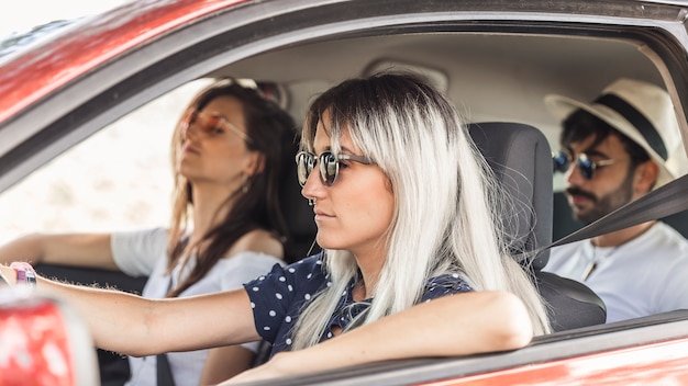 Mujer joven con sus amigos que viajan en coche moderno