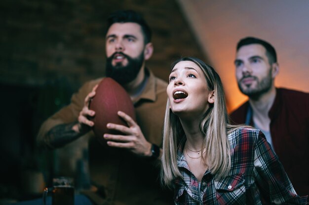 Mujer joven y sus amigos viendo el partido de rugby en la televisión con anticipación