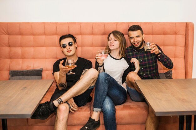 Mujer joven con sus dos amigos bebiendo bebidas en el restaurante