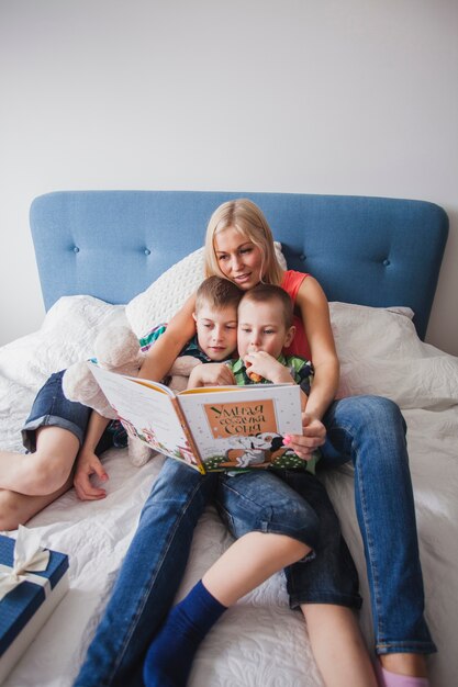 Mujer joven con sus hijos leyendo un libro