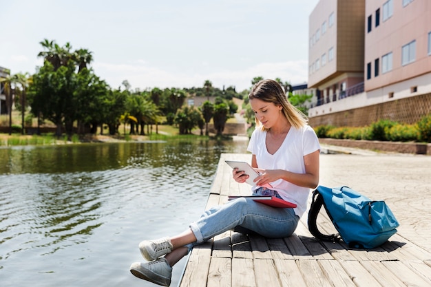Mujer joven con tableta en el campus cerca del lago