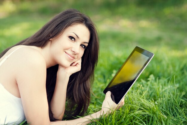 Mujer joven con tableta digital en pradera