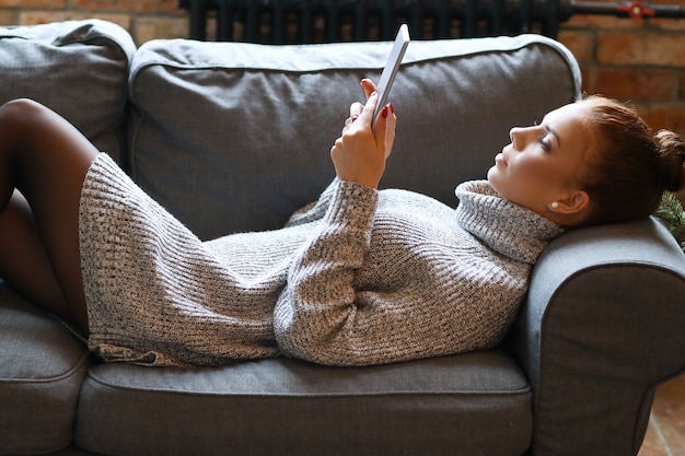 Mujer joven con tableta en el sofá