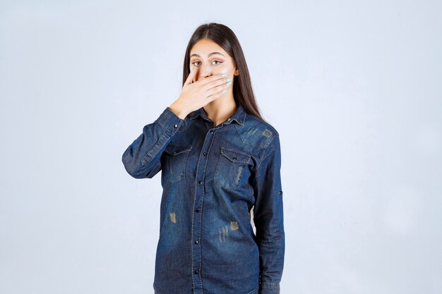 Mujer joven tapándose la boca y guarda silencio