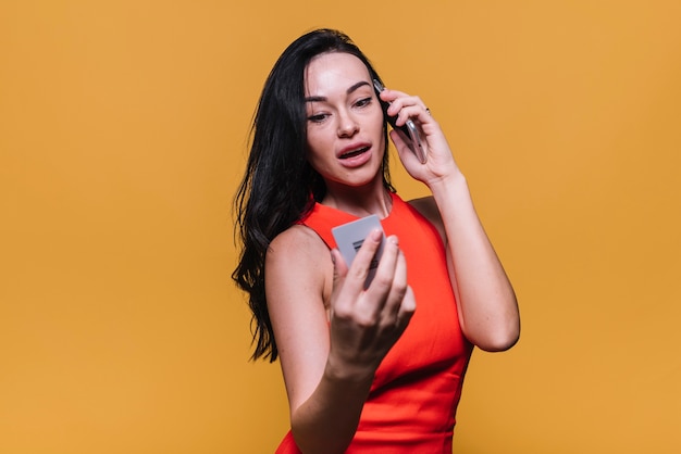 Mujer joven con tarjeta de crédito hablando por teléfono