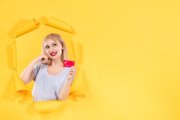 Mujer joven con tarjeta de crédito en papel amarillo rasgado fondo dinero banco venta compras