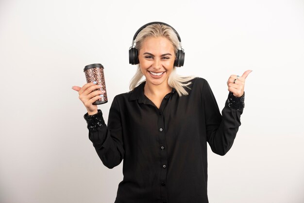 Mujer joven con taza en auriculares sobre un fondo rojo. Foto de alta calidad