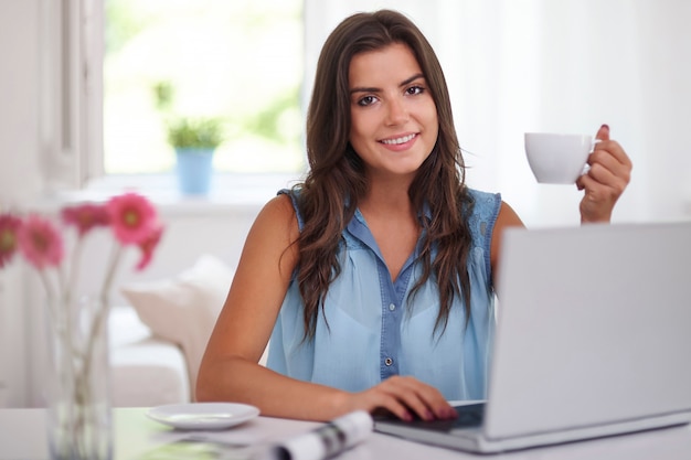 Mujer joven con taza de café y computadora portátil