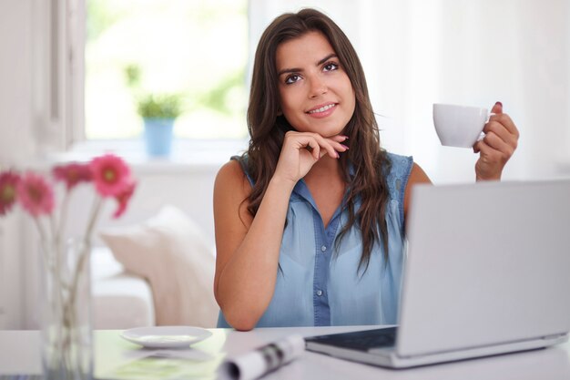 Mujer joven con taza de café y computadora portátil