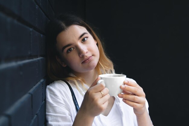 Una mujer joven con una taza de café en el interior de un café negro