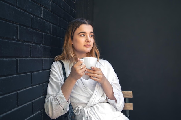 Una mujer joven con una taza de café en el interior de un café negro