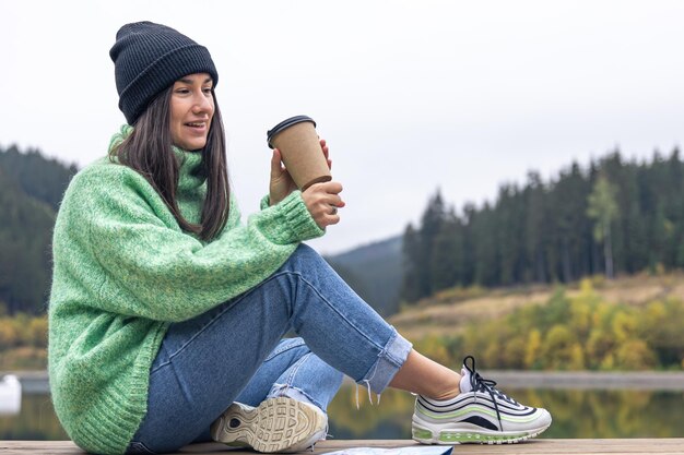 Una mujer joven con una taza de café y un mapa sobre un fondo de montañas