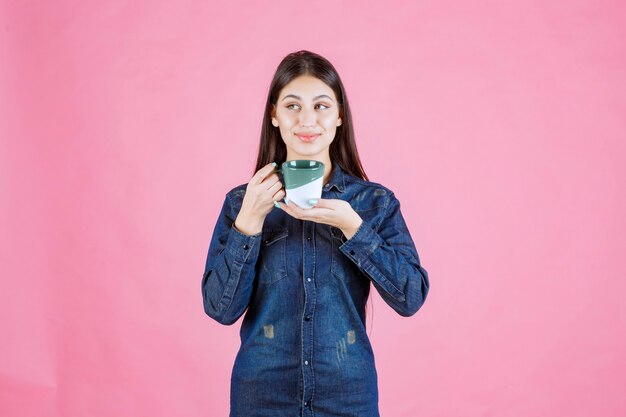 Mujer joven con una taza de café sonriendo y sintiéndose positivo