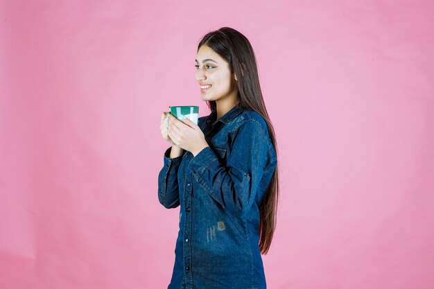 Mujer joven con una taza de café sonriendo y sintiéndose positivo