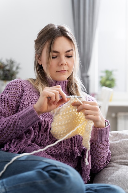 Foto gratuita mujer joven tejiendo mientras se relaja