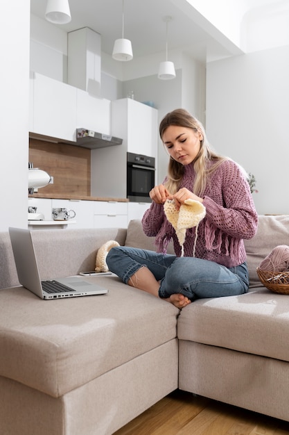 Foto gratuita mujer joven tejiendo mientras se relaja