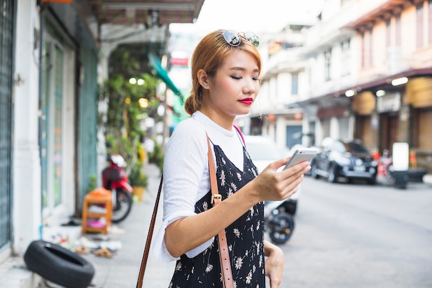Mujer joven con teléfono inteligente en la calle