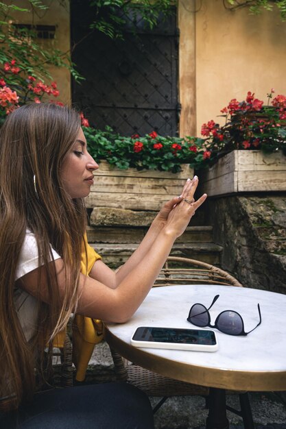 Una mujer joven con teléfono inteligente y gafas de sol en un café en la terraza