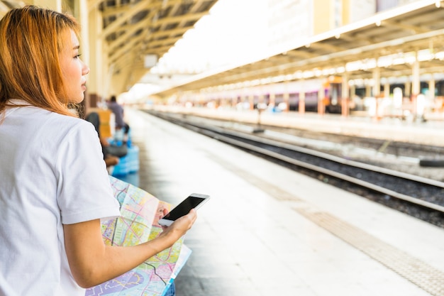 Mujer joven con teléfono inteligente y mapa