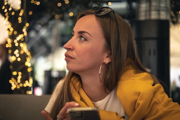 Una mujer joven con un teléfono inteligente en sus manos sobre un fondo borroso