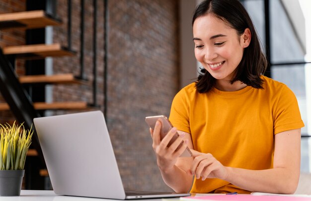 Mujer joven con teléfono mientras asiste a clases en línea