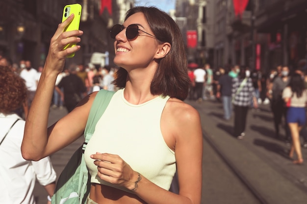 Mujer joven con teléfono móvil viaja por las concurridas calles de Estambul feliz disfrutando de la belleza de la ciudad