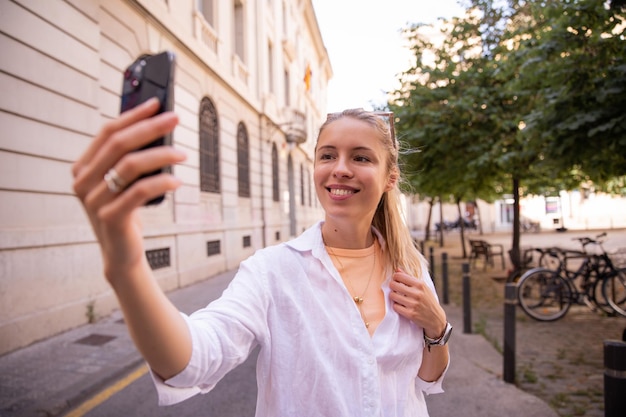 Mujer joven con teléfono sonríe a la ciudad