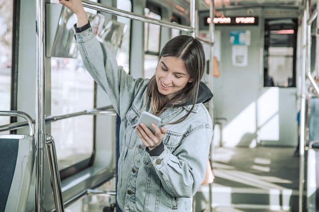 Mujer joven con teléfono en transporte público.