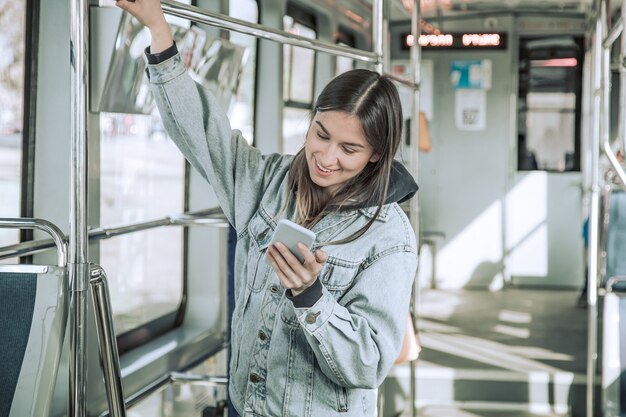 Mujer joven con teléfono en transporte público.