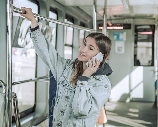 Mujer joven con teléfono en transporte público.