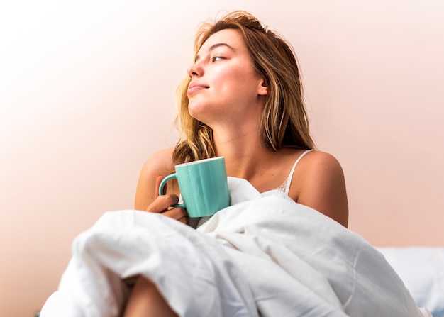 Foto gratuita mujer joven tendido en la cama y mirando a otro lado