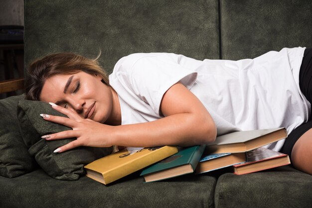 Foto gratuita mujer joven tendido en el sofá lleno de libros.