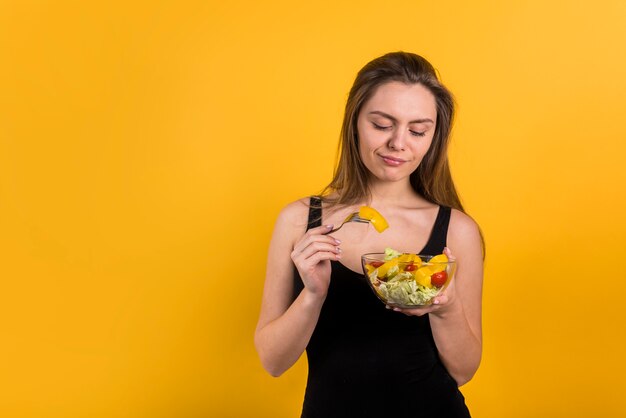 Mujer joven con tenedor y plato de ensalada