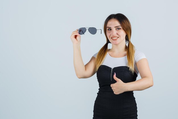 Mujer joven, tenencia, anteojos, mientras, actuación, pulgares arriba