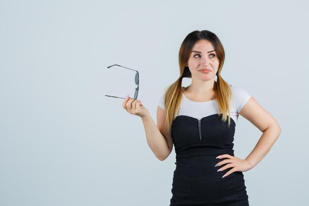 Mujer joven, tenencia, anteojos, mientras, mantener la mano, en, cadera